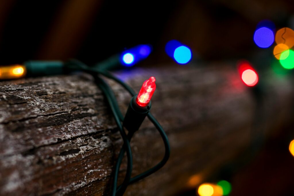 Close-up of colorful string lights wrapped around a wooden log, creating a cozy and festive atmosphere.